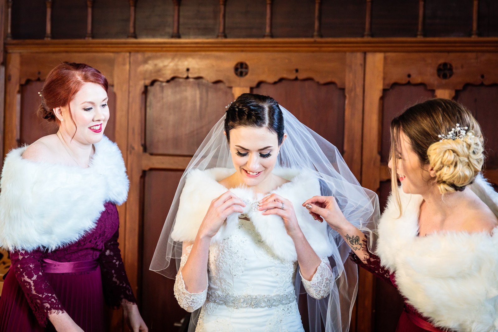 Bride with two bridesmaids in fur stoles at the carved church door