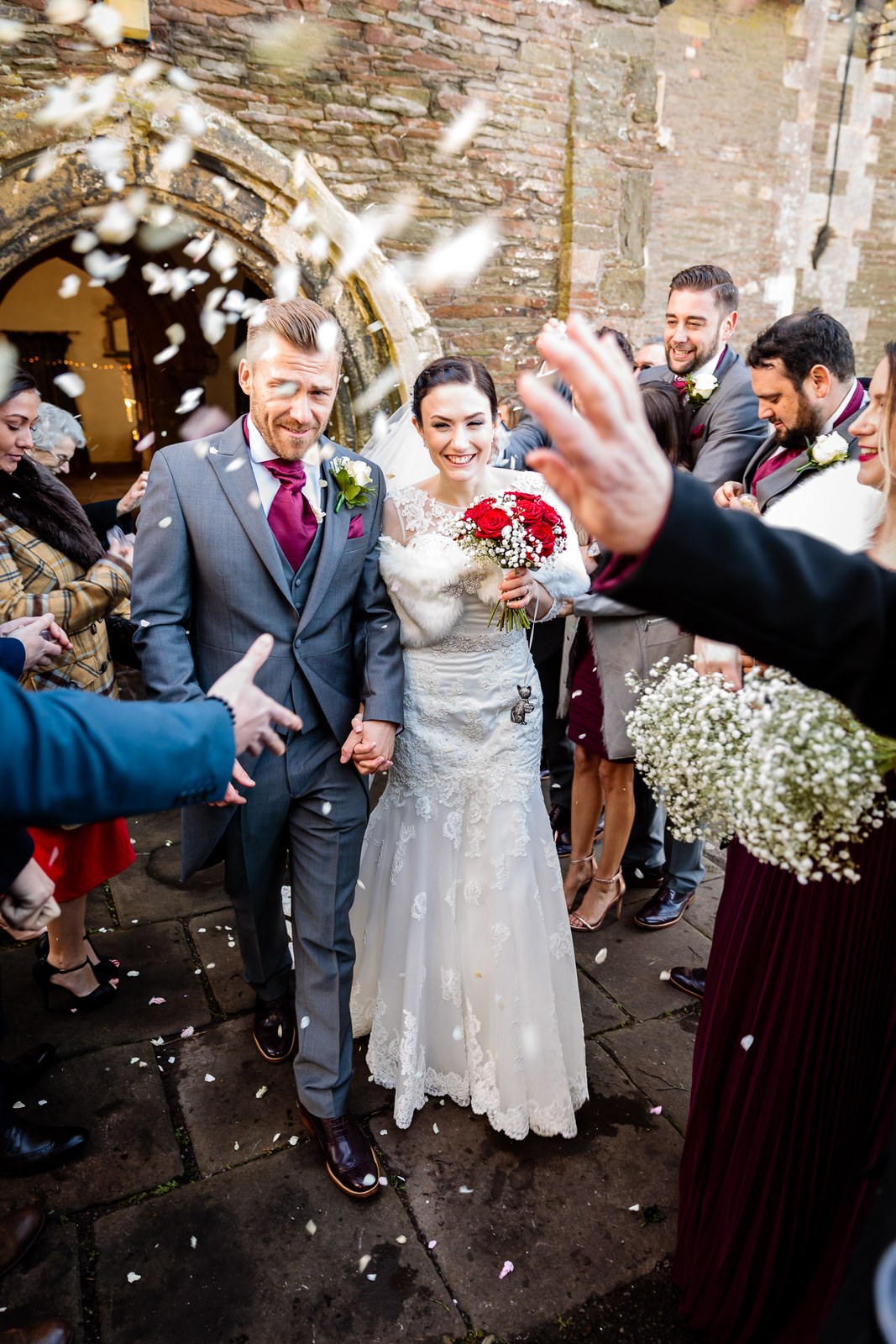 Confetti showers the couple beneath the church's stone archway
