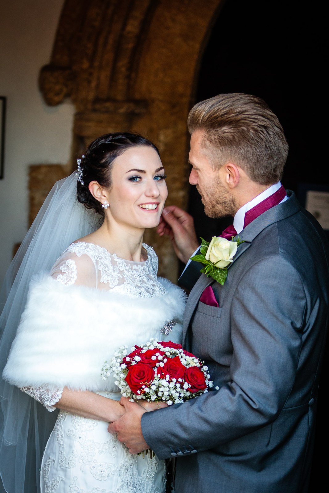 Bride and groom in the arched porch, her veil catching the light