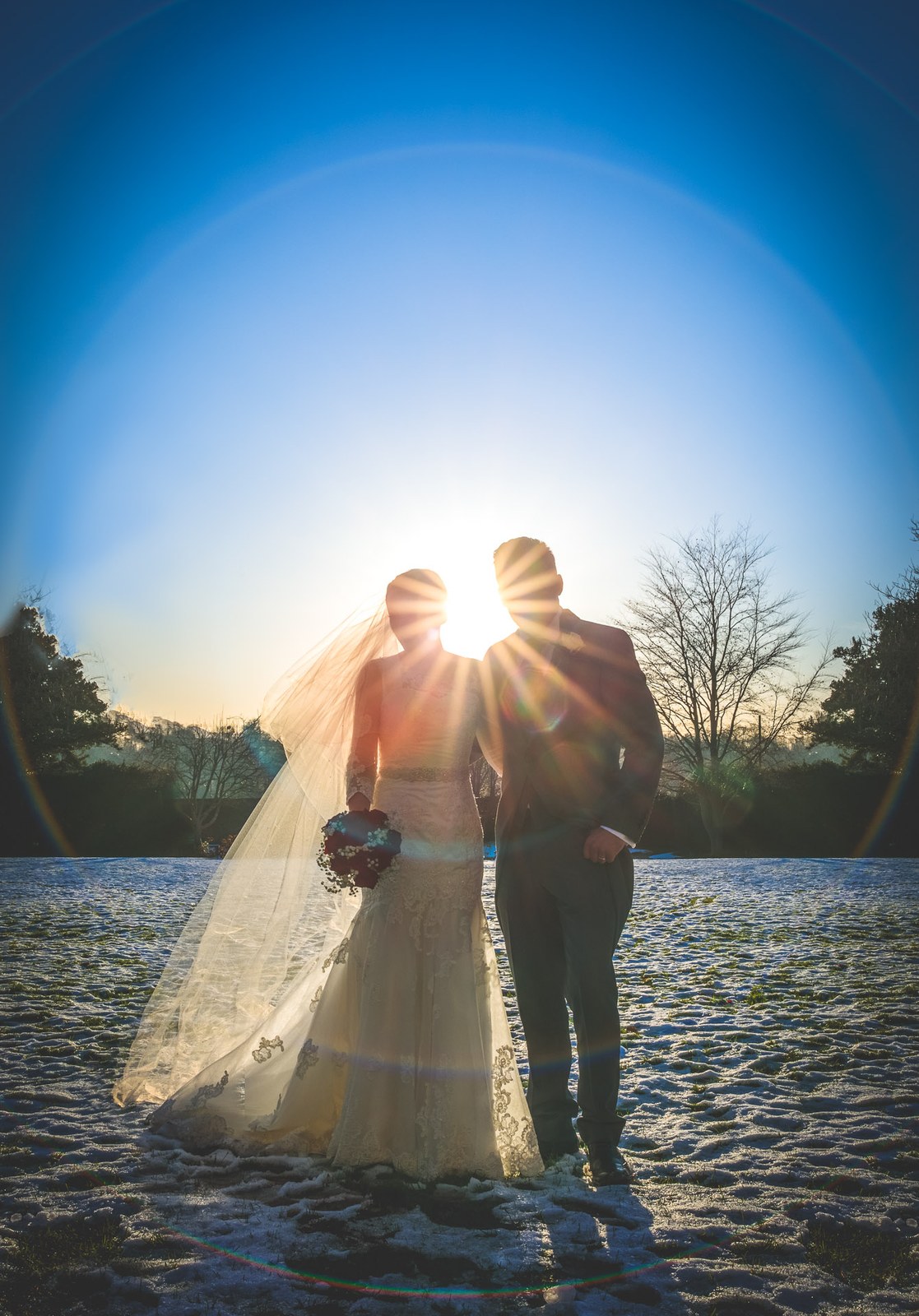 The couple silhouetted against a bright winter sun on a snowy field
