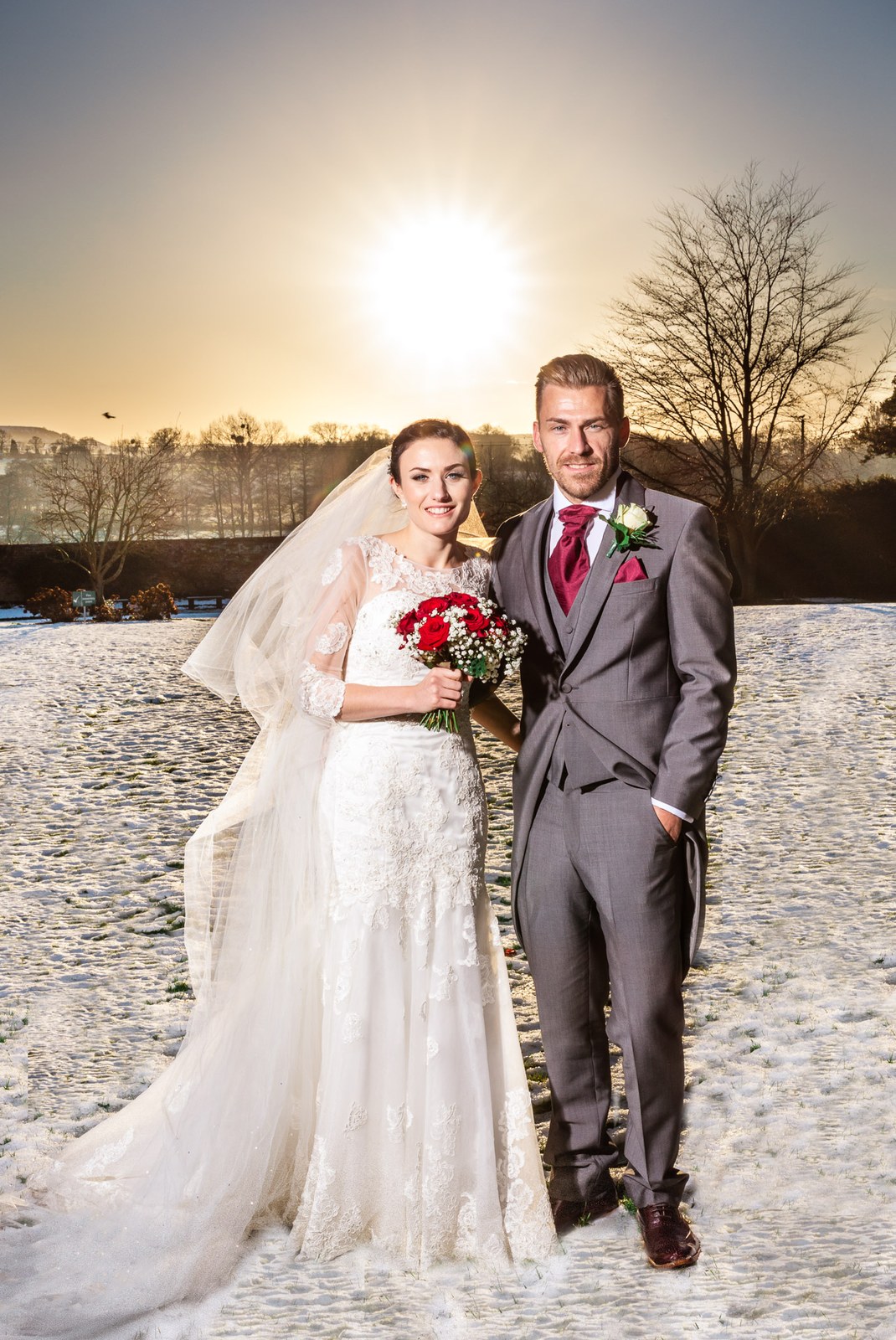 Bride and groom on the frosted parkland beneath a low golden sun