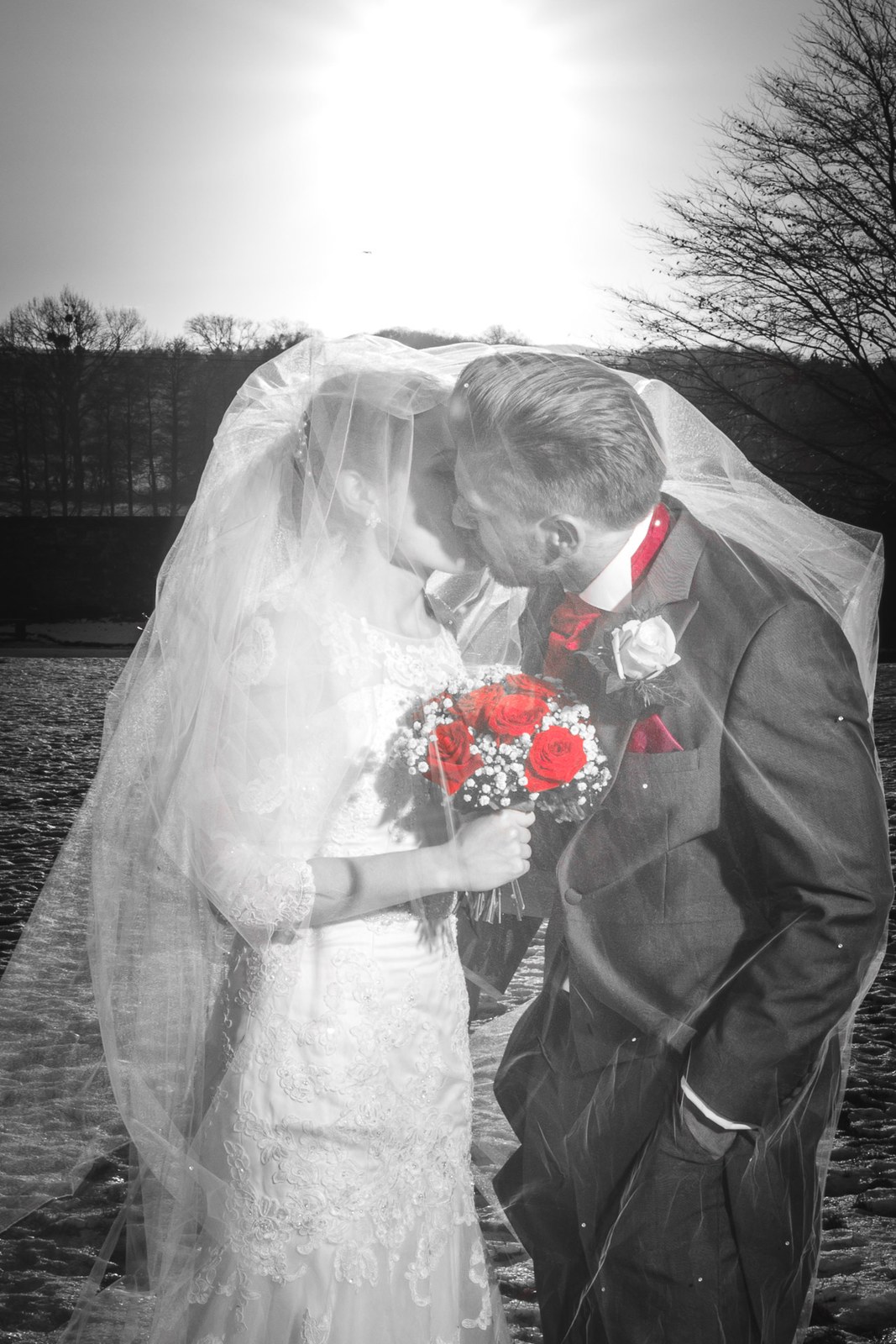 Black and white of the couple kissing under the veil in the snow