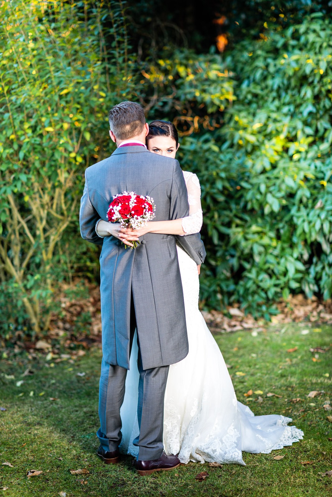 The bride wraps her arms around the groom in a garden embrace