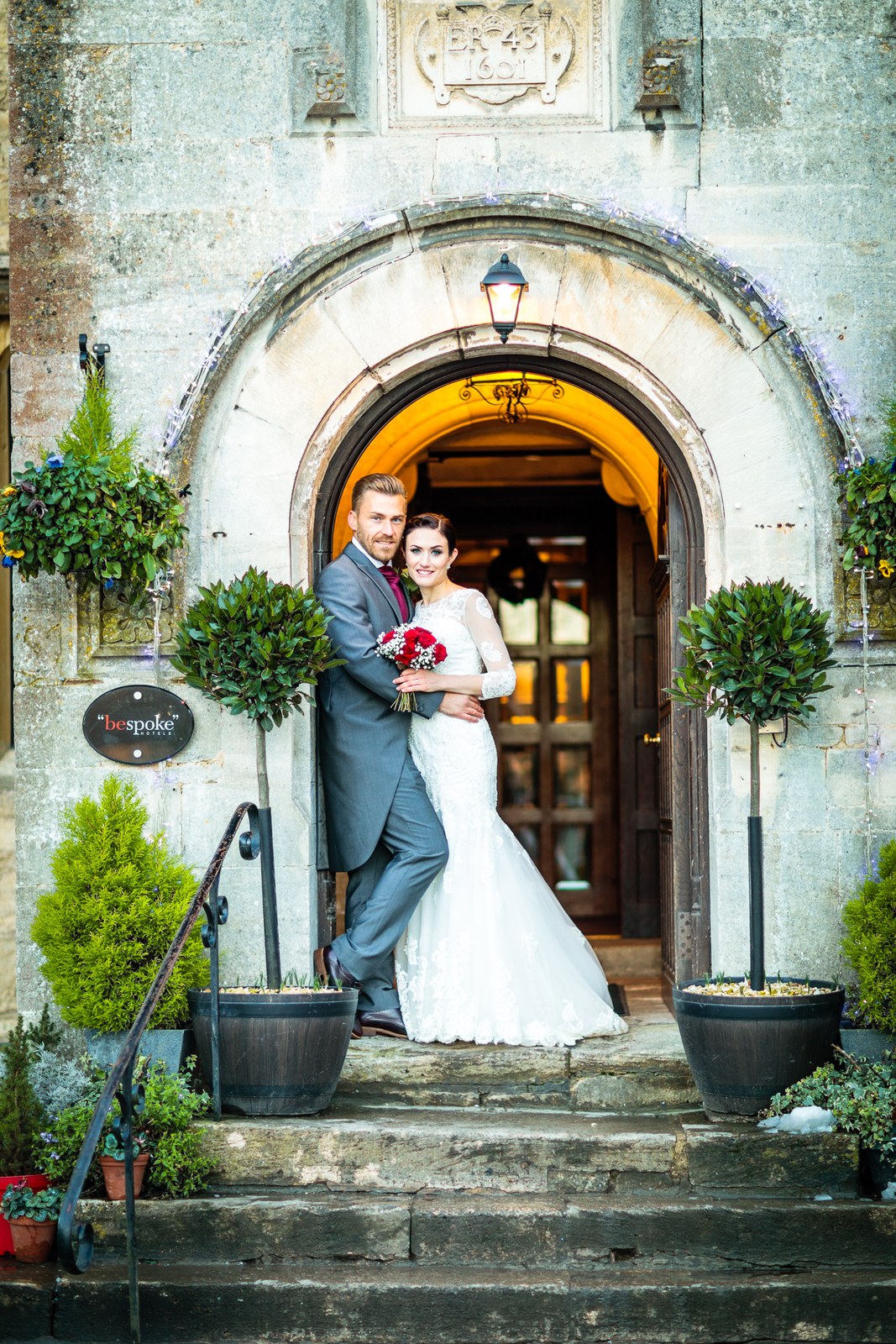 Bride and groom kiss on the steps beneath the Stonehouse Court Hotel archway