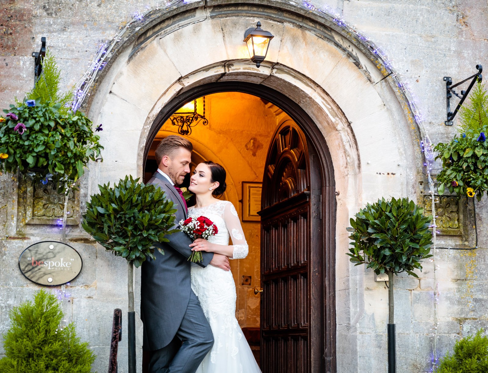 The couple embrace within the warm arched doorway of Stonehouse Court Hotel