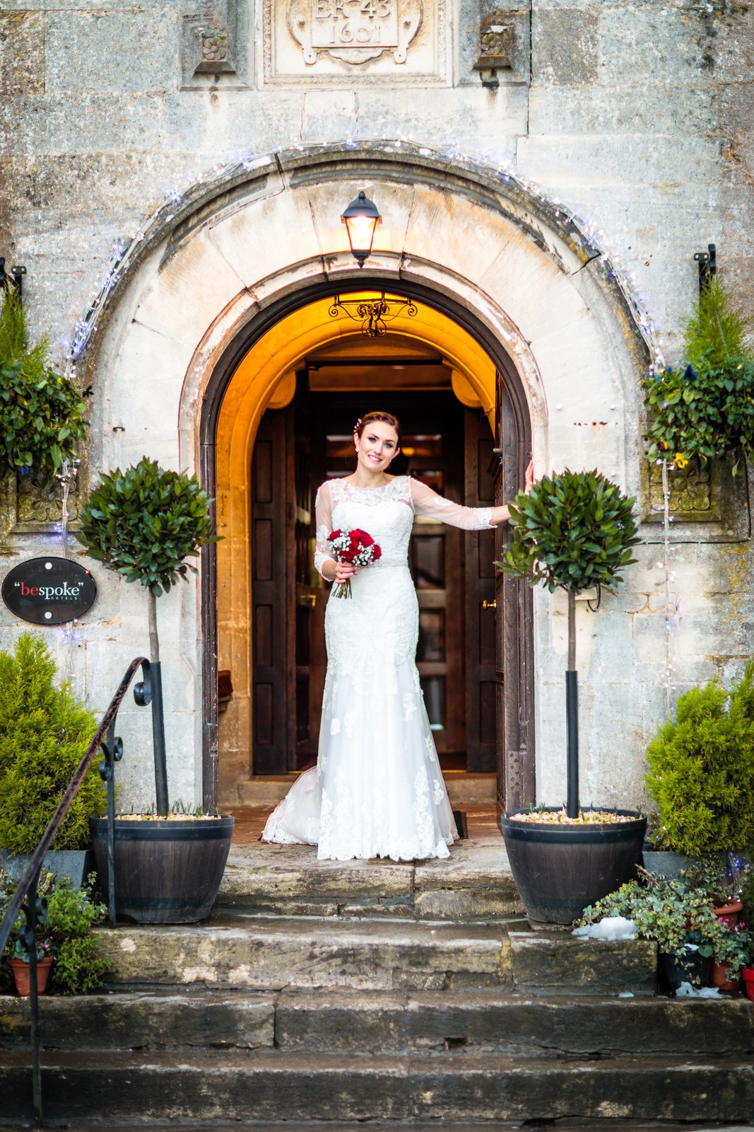 Bride alone in the grand arched doorway of Stonehouse Court Hotel