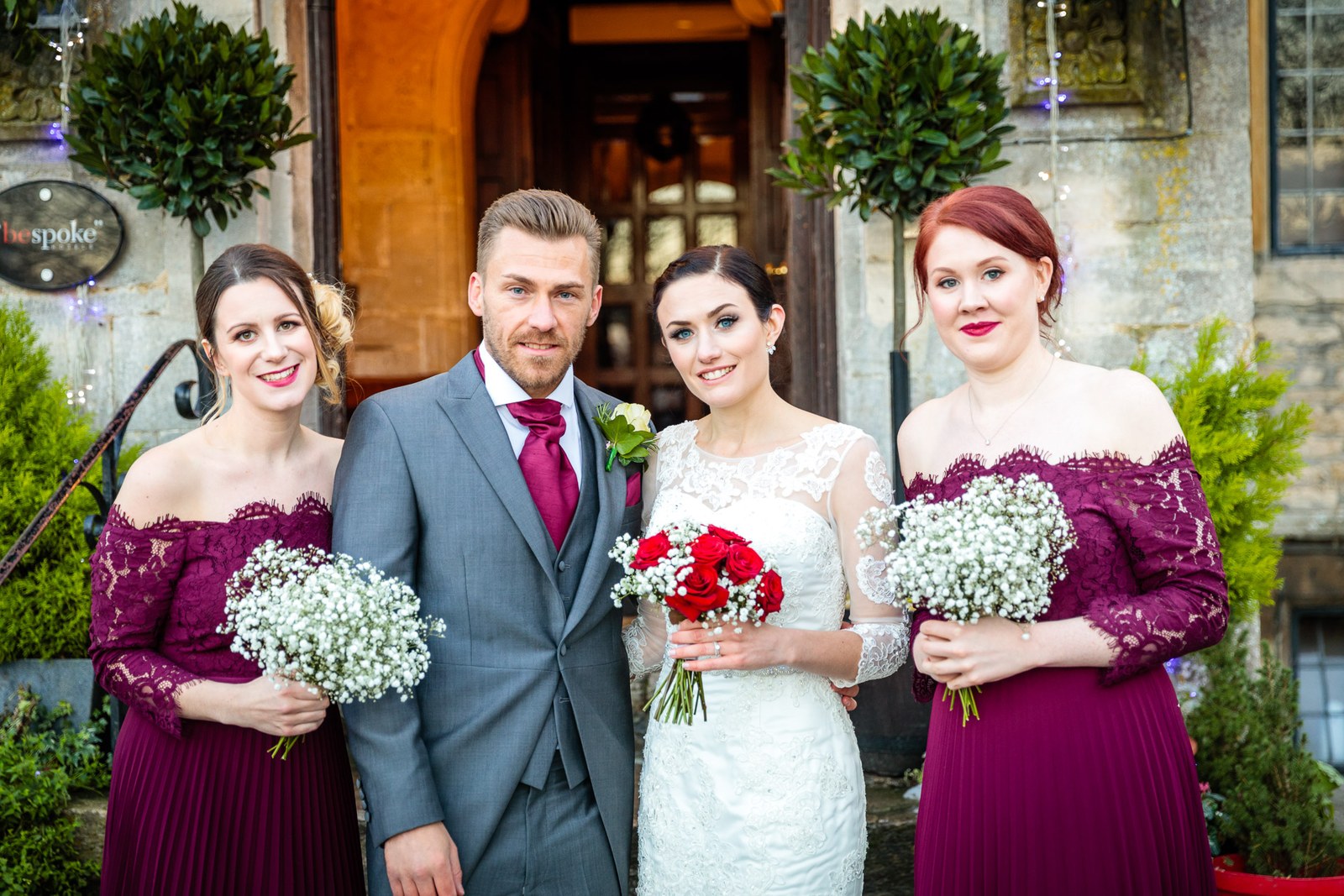 The groom with the bride and two bridesmaids outside Stonehouse Court Hotel