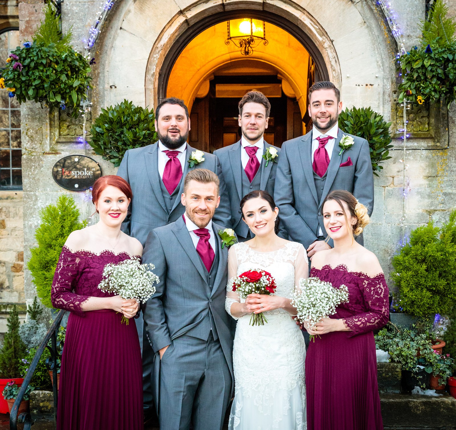 The wedding party on the steps of Stonehouse Court Hotel, bridesmaids in burgundy