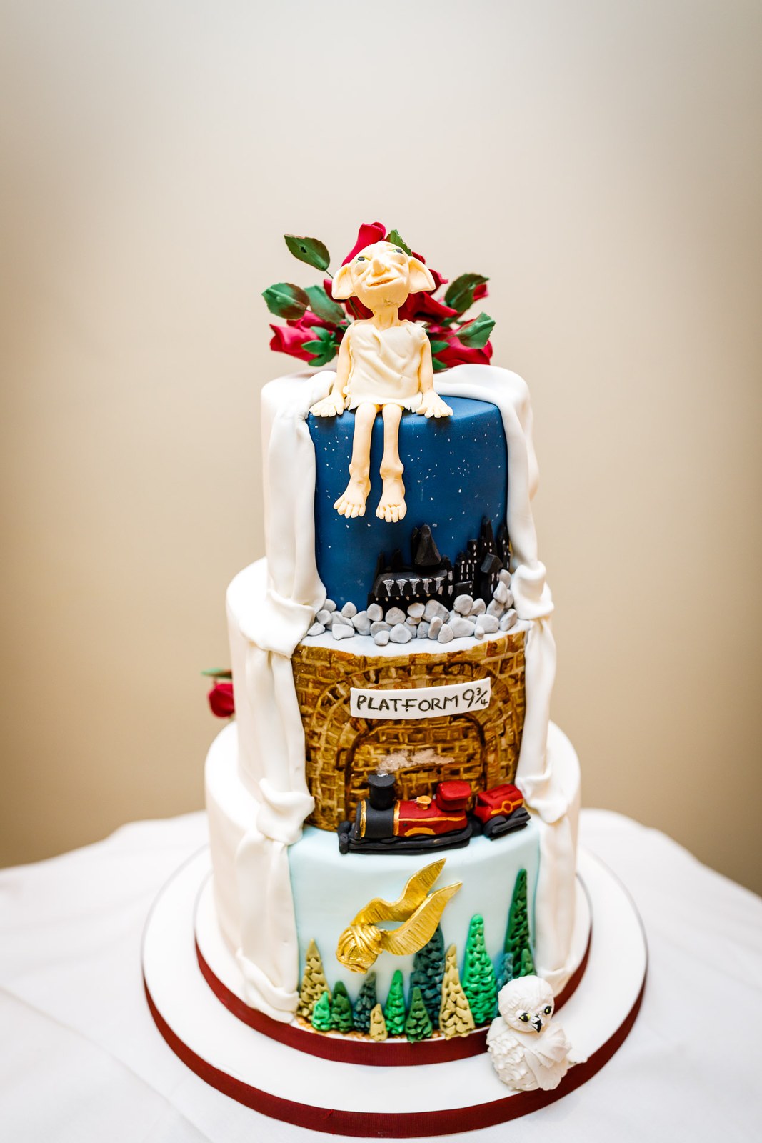A tiered white wedding cake with a whimsical Platform 9¾ storybook theme