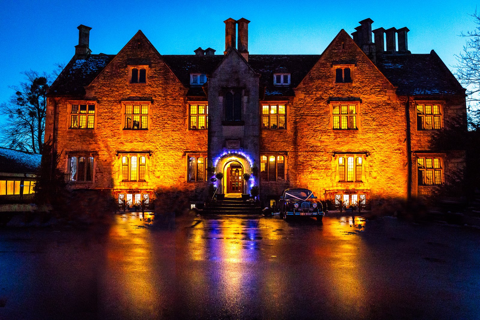 Stonehouse Court Hotel floodlit against the blue dusk, reflected on wet ground
