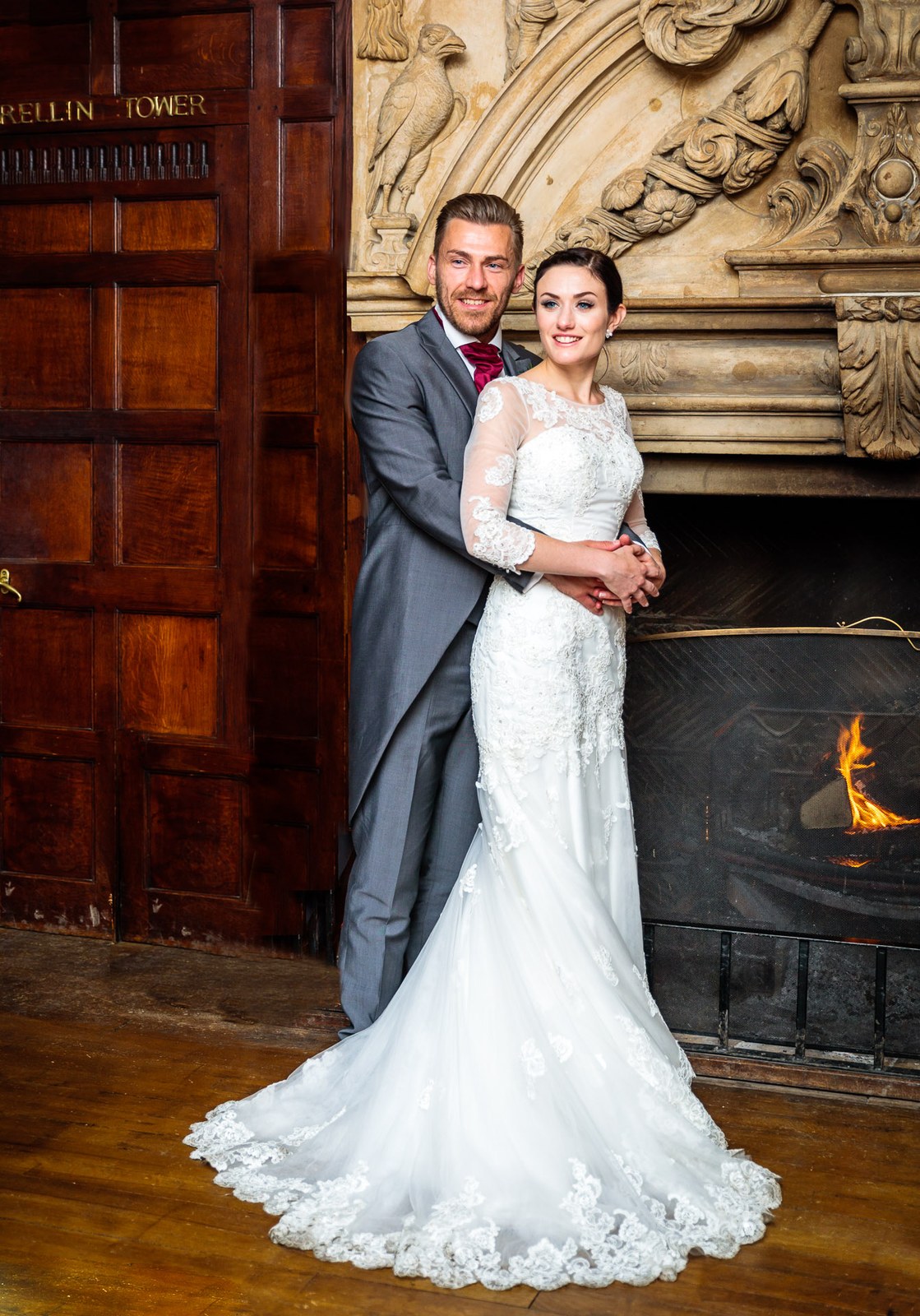 Bride and groom by a blazing panelled fireplace inside Stonehouse Court Hotel