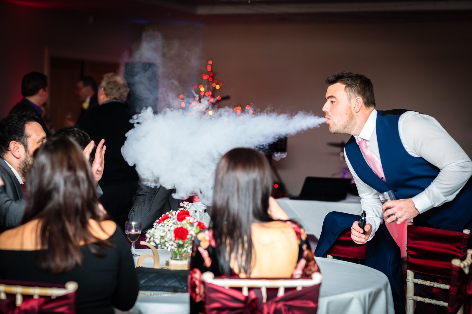 A guest blows a great cloud of vapour across the tables during the reception