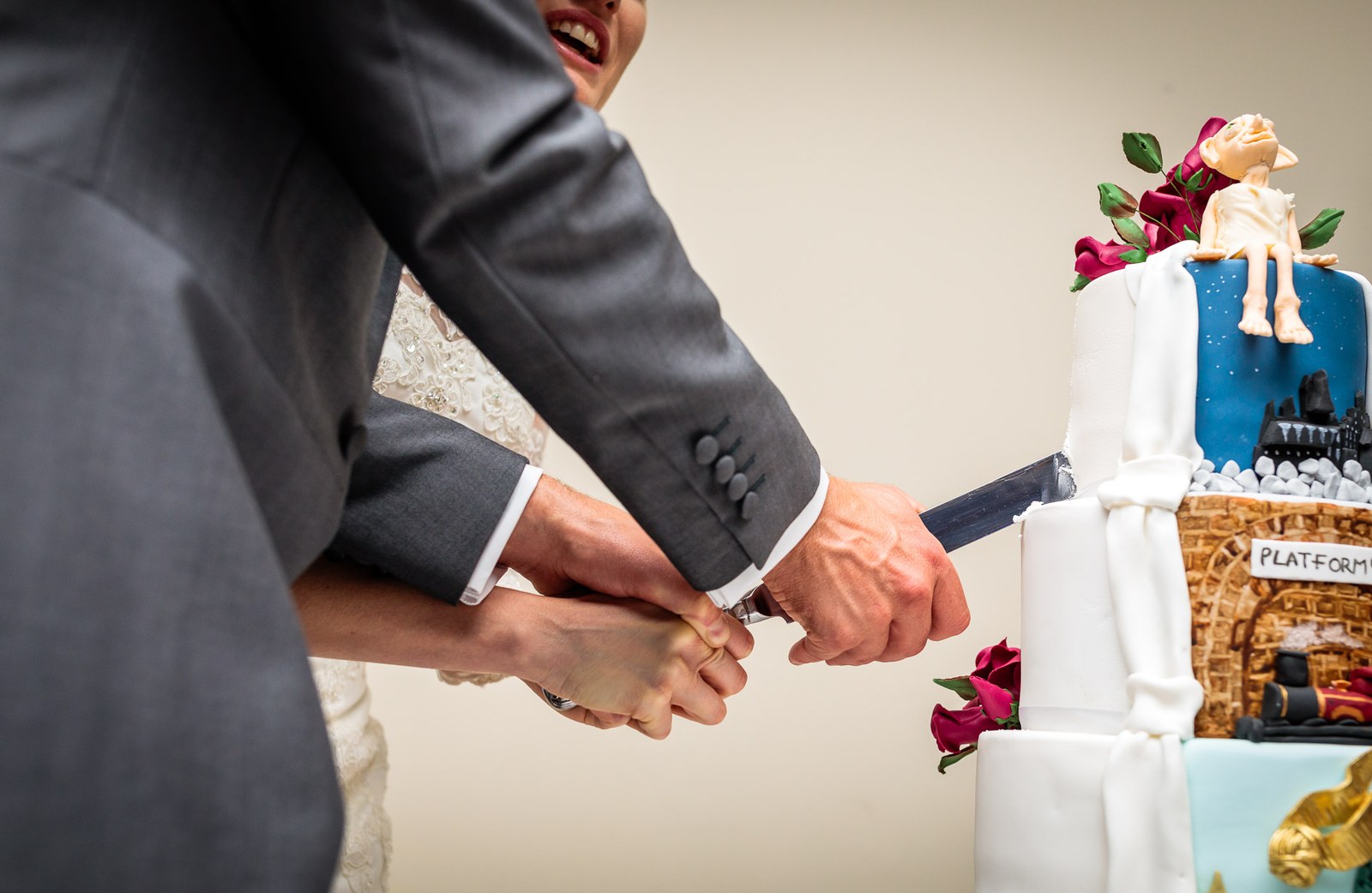 Close-up of the couple's hands cutting the storybook-themed wedding cake