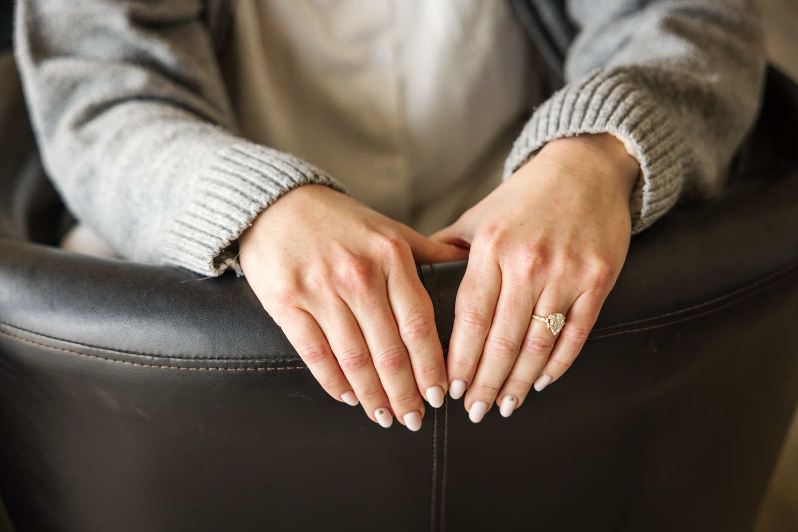 The bride's hands resting on the back of a chair, her engagement ring showing.