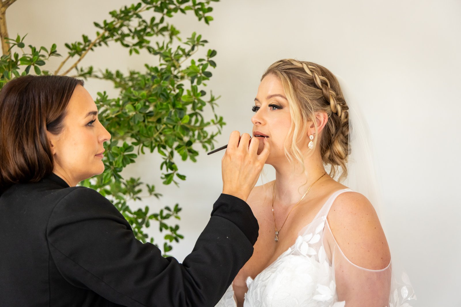 A makeup artist working on the bride's lips in the bridal suite at Stratton Court Barn.