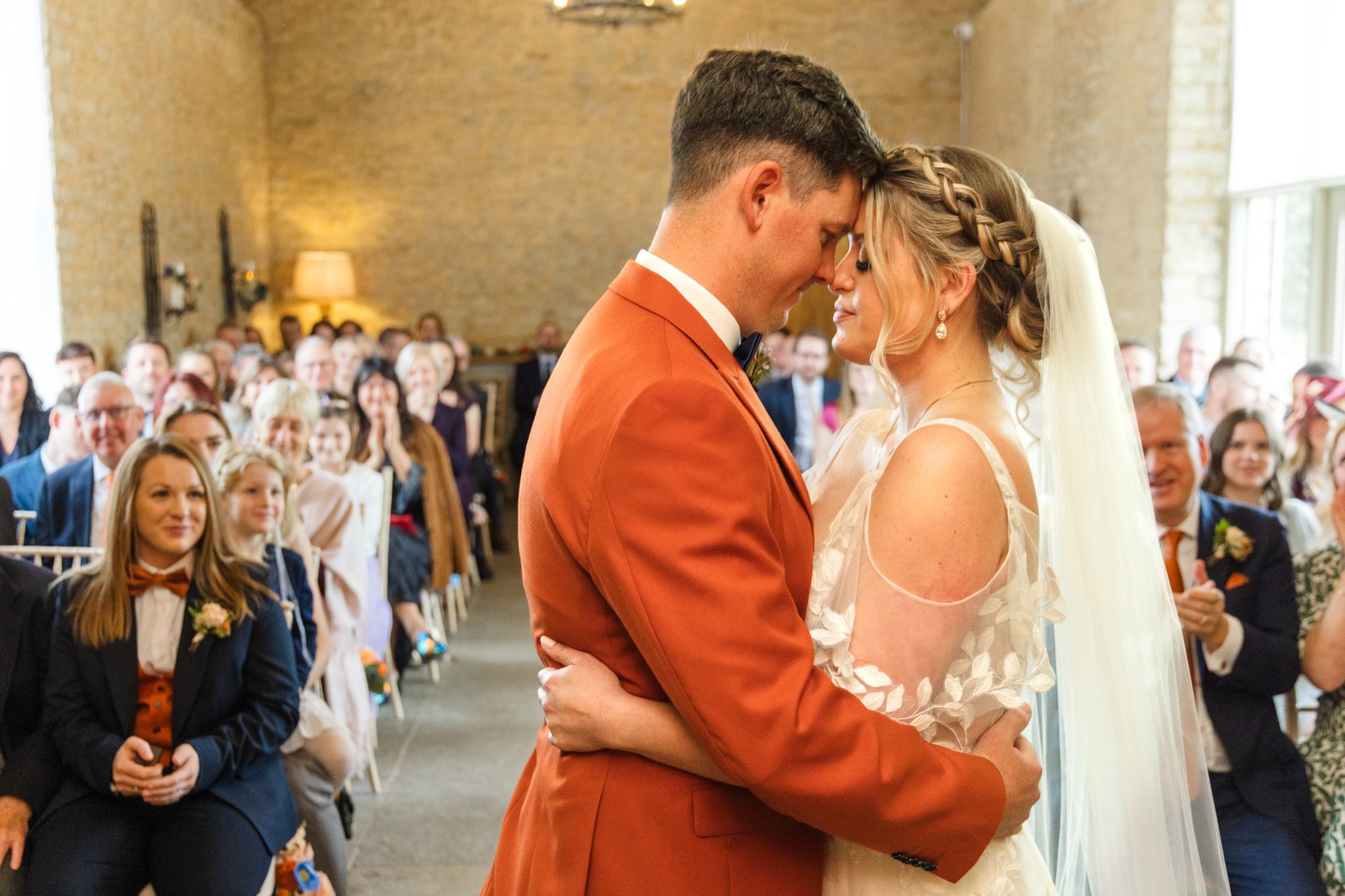 The bride and groom resting their foreheads together as guests watch from both sides.