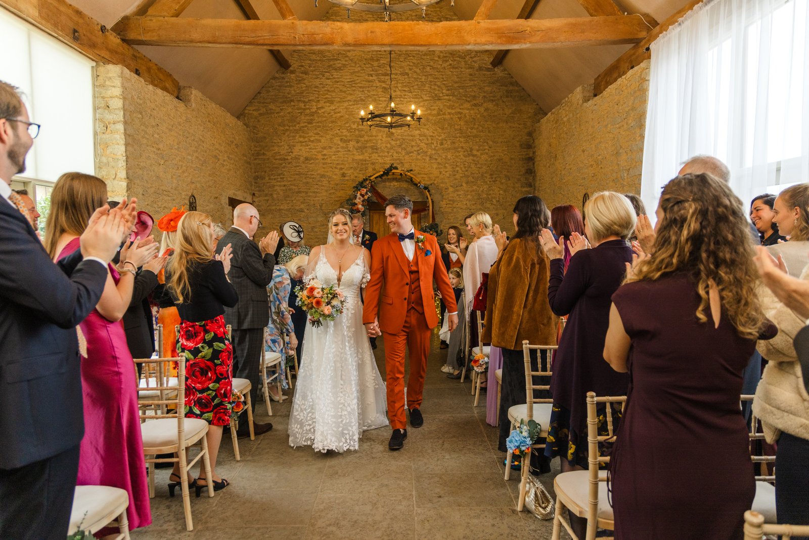 The newly married couple back down the aisle under the timber roof at Stratton Court Barn.