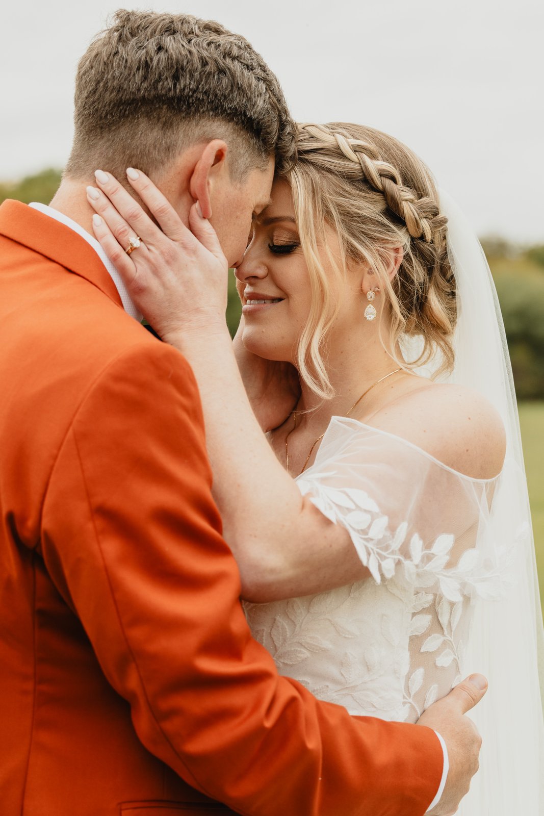 The groom holding the bride's face in his hands out on the lawn.