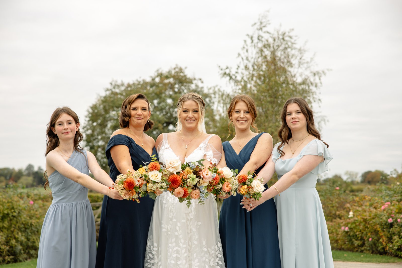 The bride and four bridesmaids in navy and pale blue holding their bouquets together.