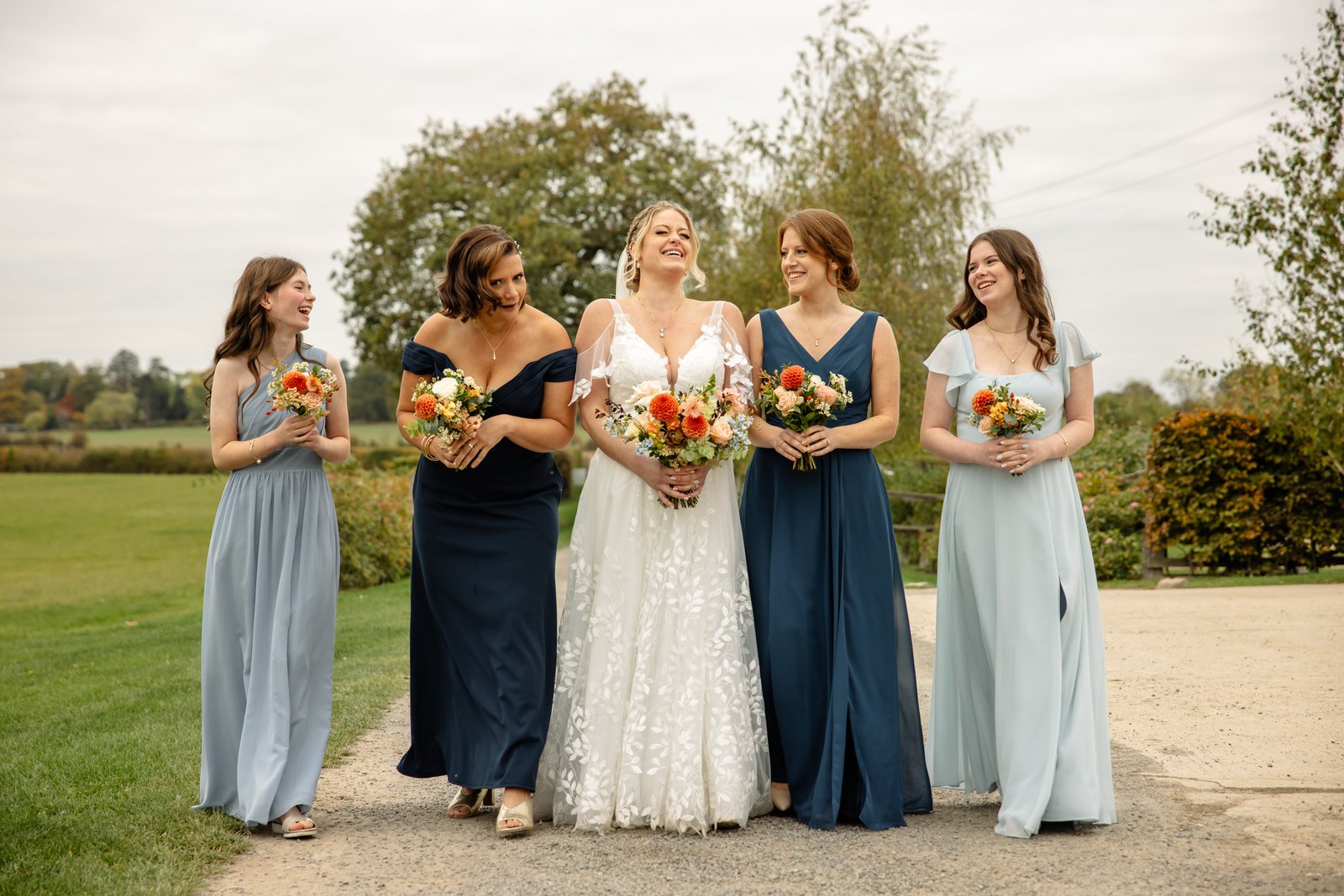 The bride and her bridesmaids walking along the gravel path in the grounds.