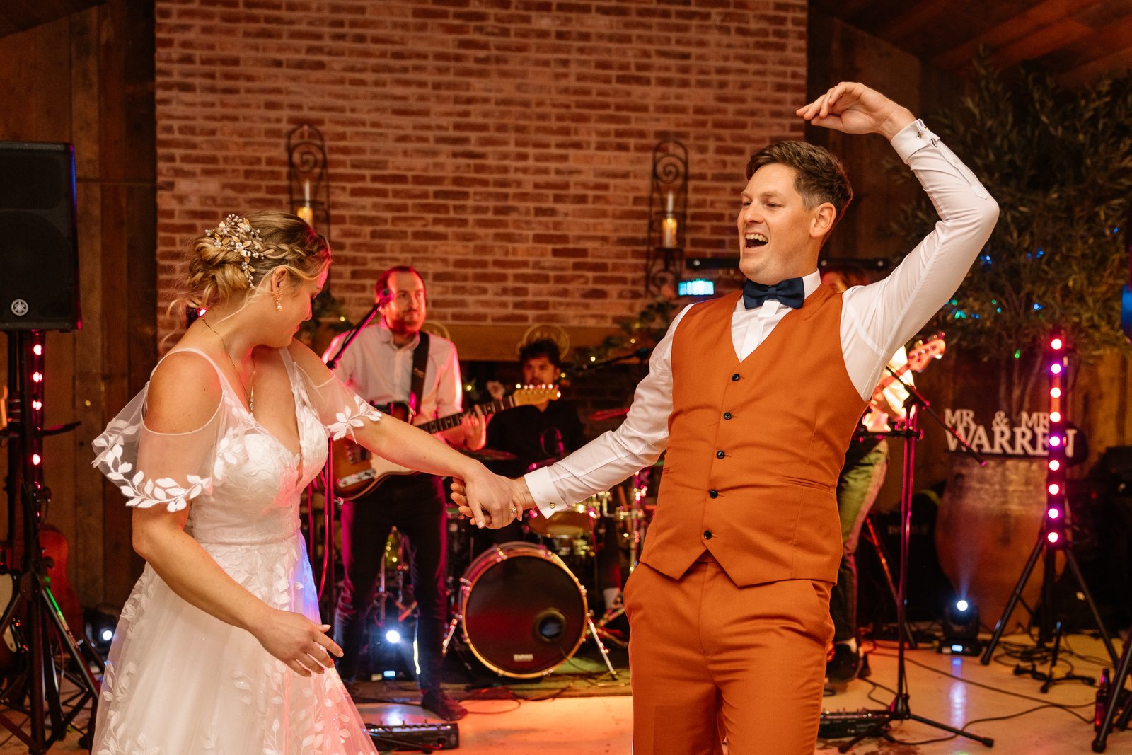 The bride and groom dancing hand in hand with the band playing behind them.