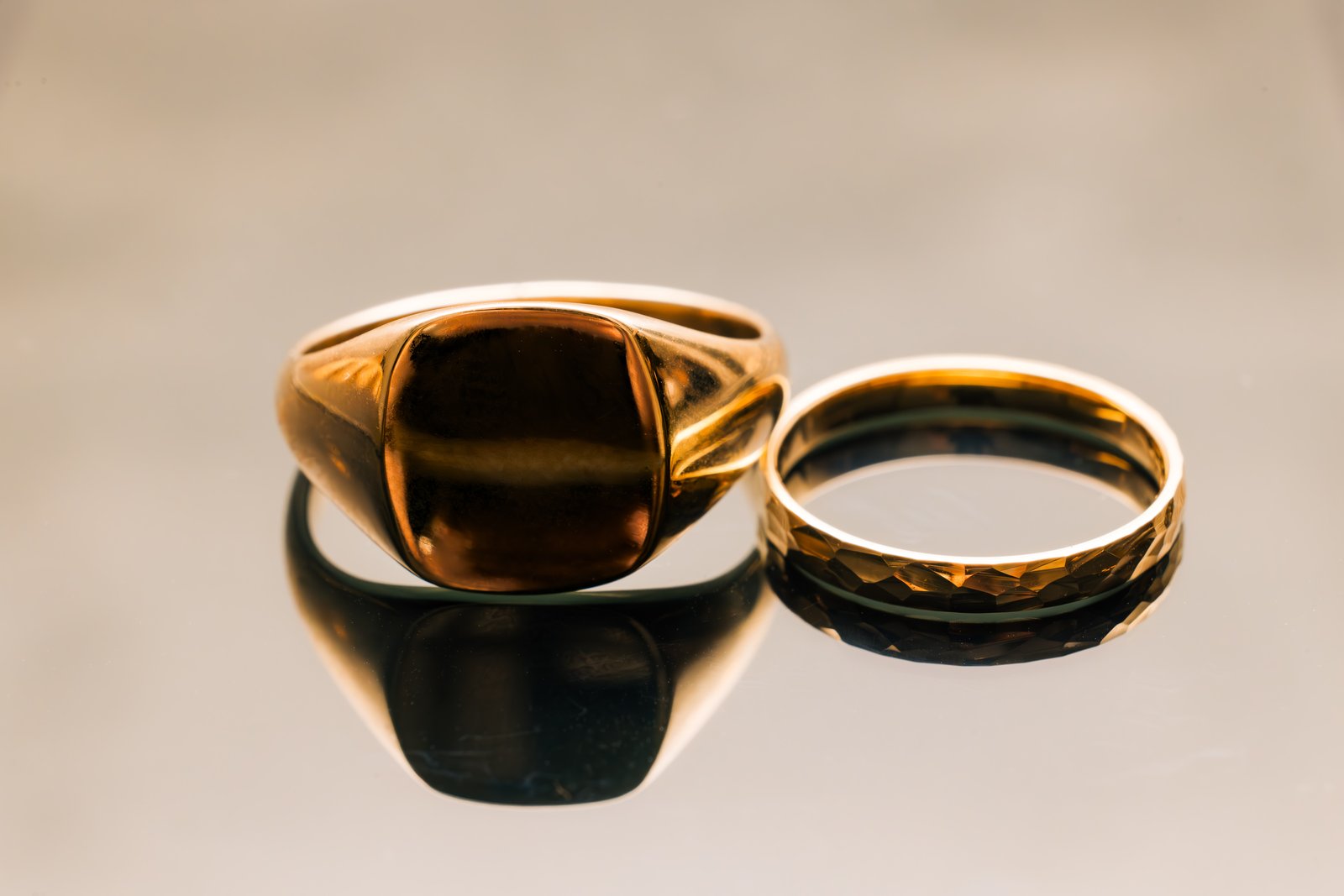 A gold signet ring and a gold wedding band resting side by side.