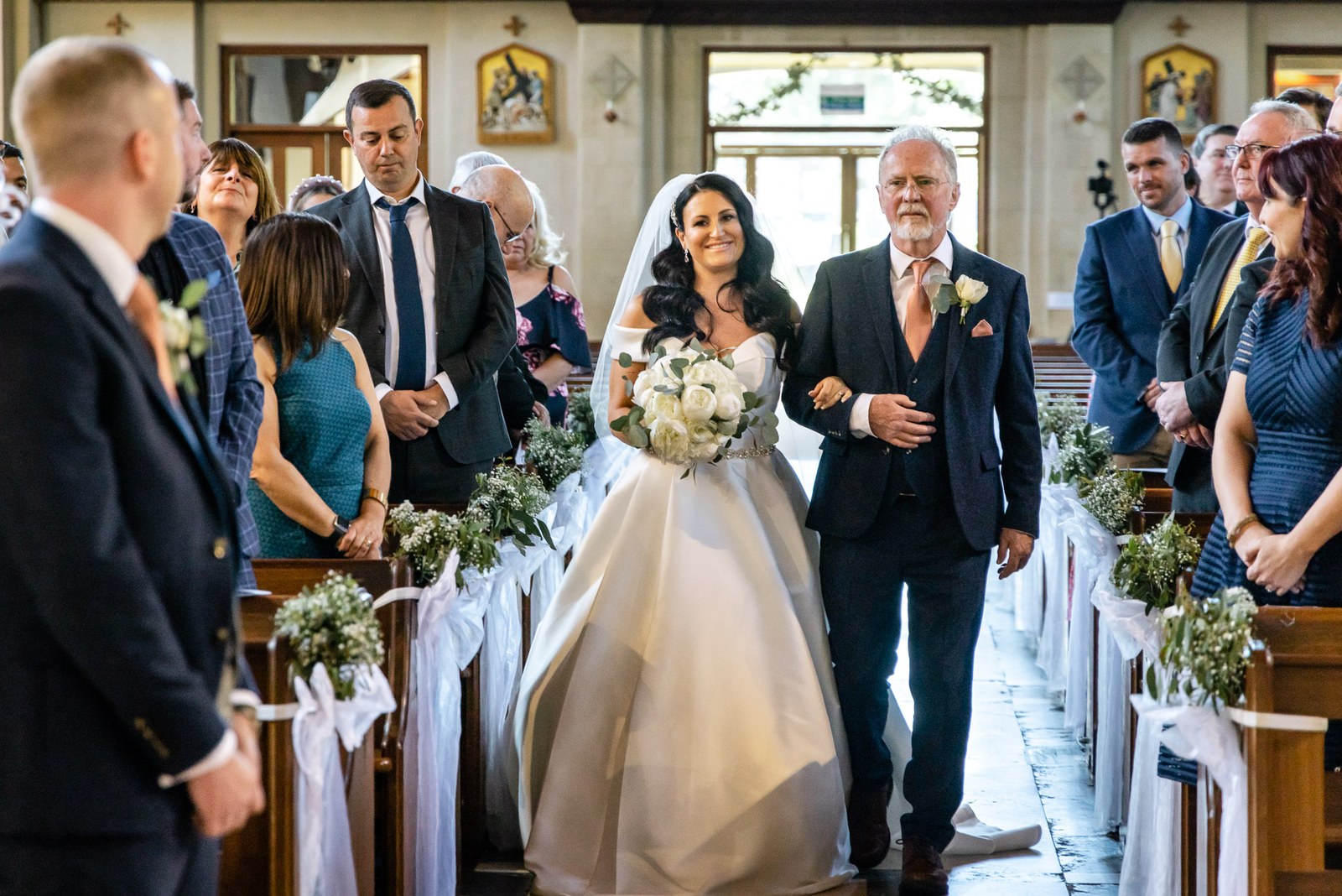 Bride walking down the aisle on her father's arm as guests stand