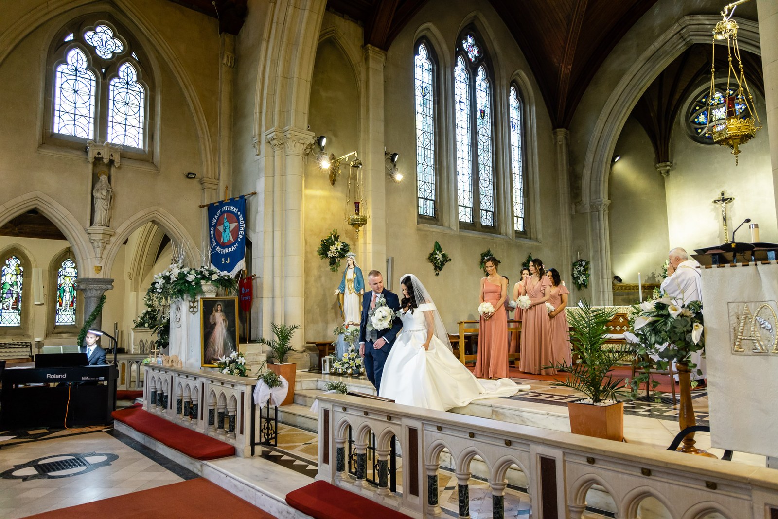 Wide view of the church interior during the ceremony beneath stained glass