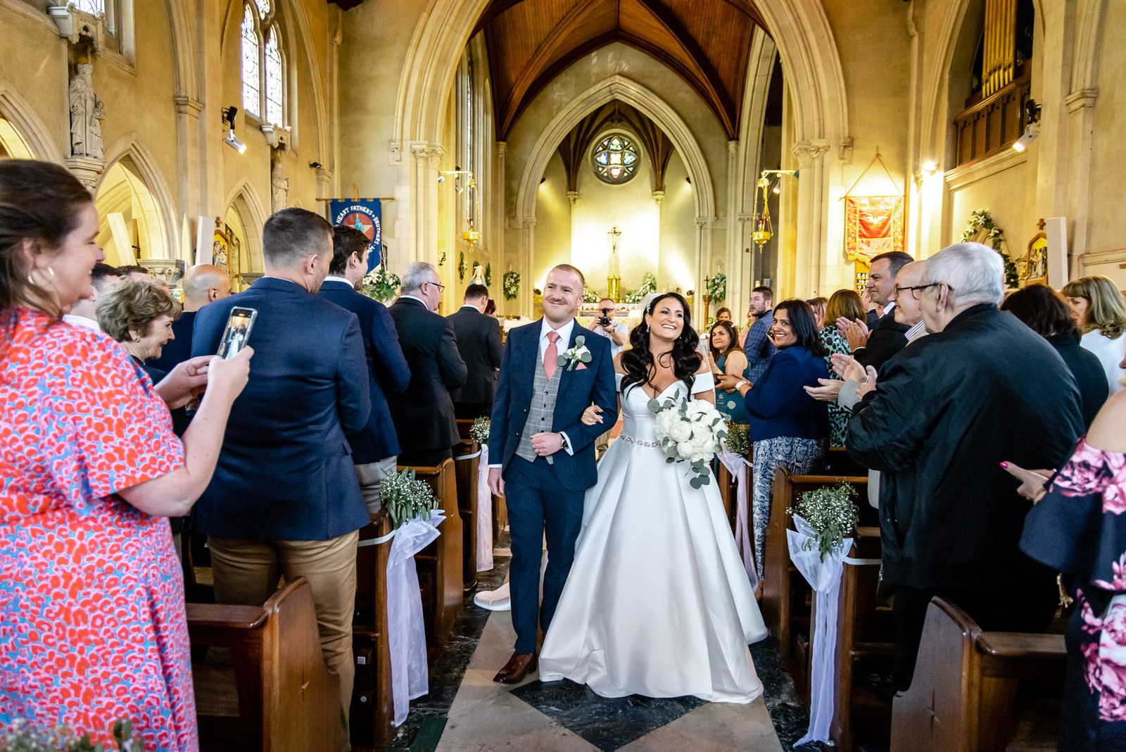 The newlyweds walking back down the aisle as guests applaud