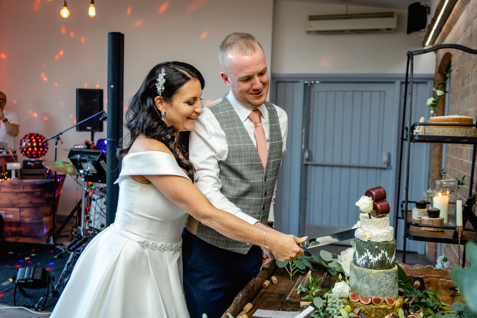 The couple cutting their wedding cake at Swallows Nest Barn as the band plays