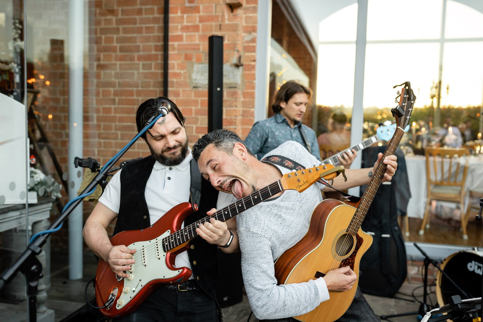 The band's guitarists performing against the brick wall at Swallows Nest Barn