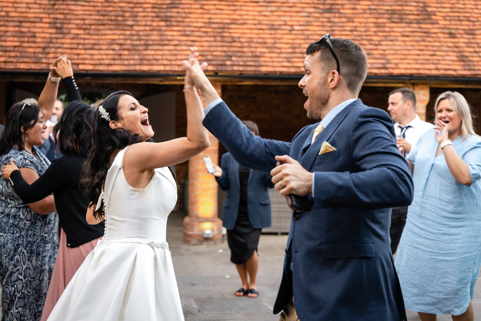 A guest twirling the bride as others dance outside Swallows Nest Barn