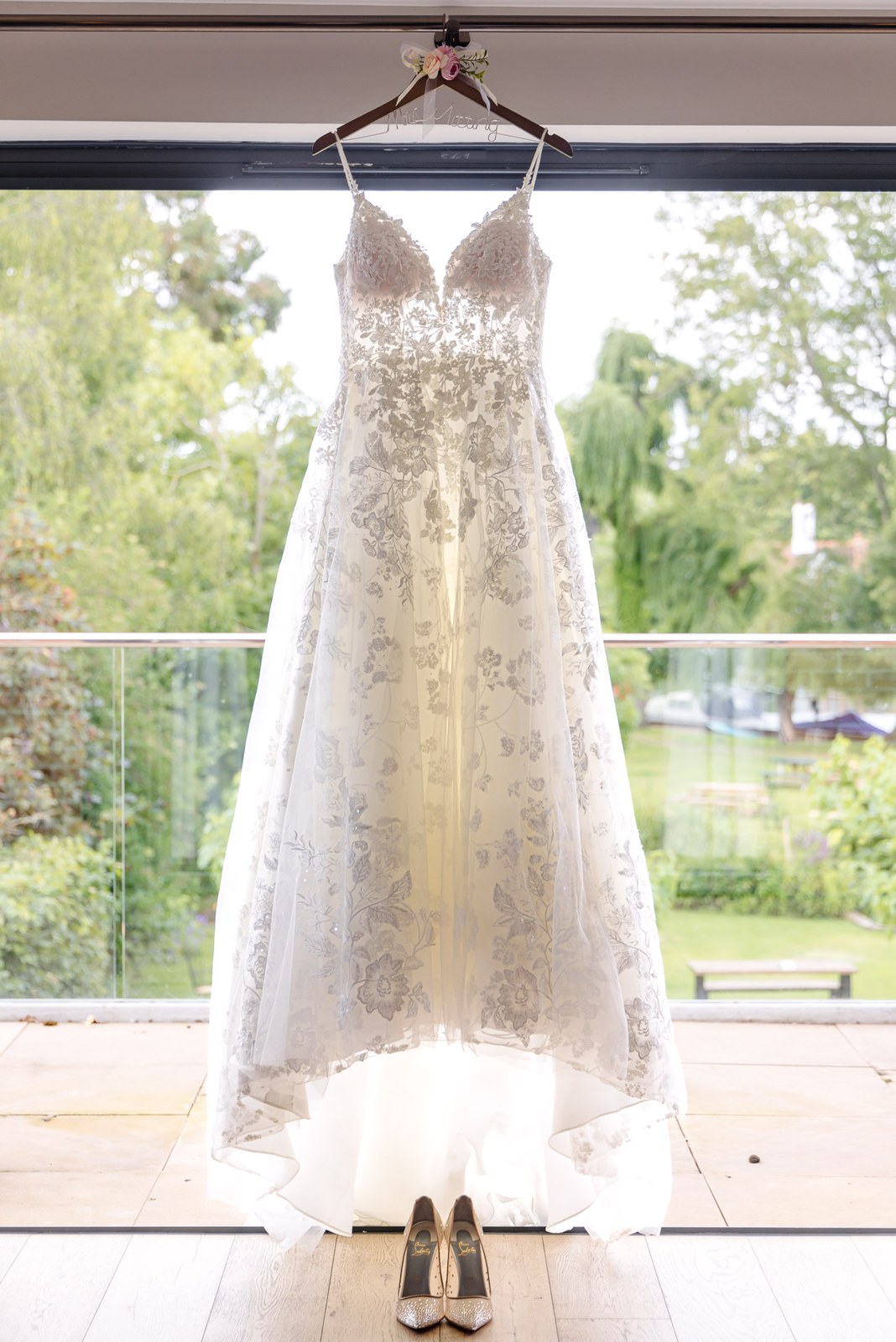 The lace wedding gown hanging in a window overlooking the grounds at The Swan at Streatley