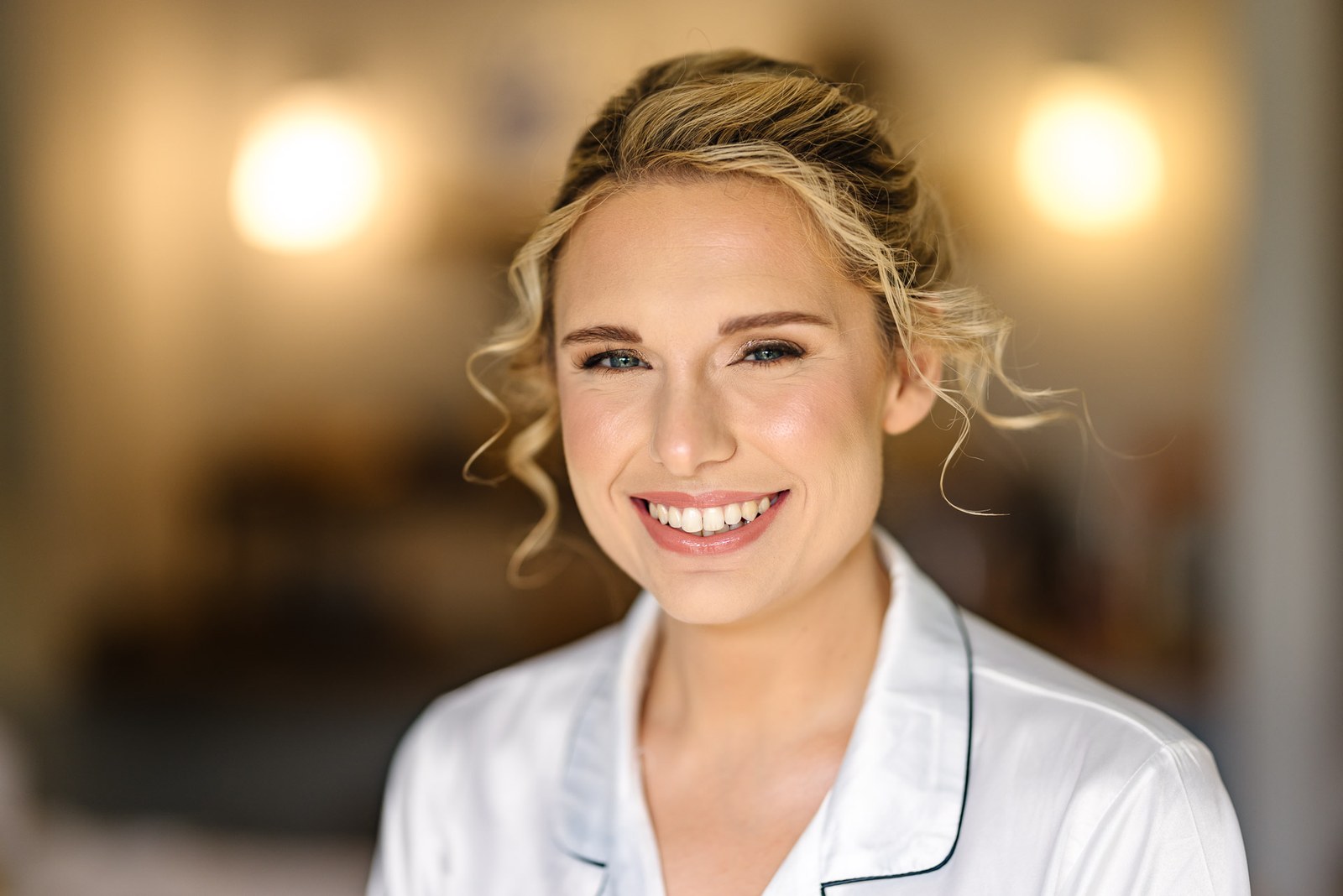 Smiling portrait of the bride in a white satin robe with her hair styled