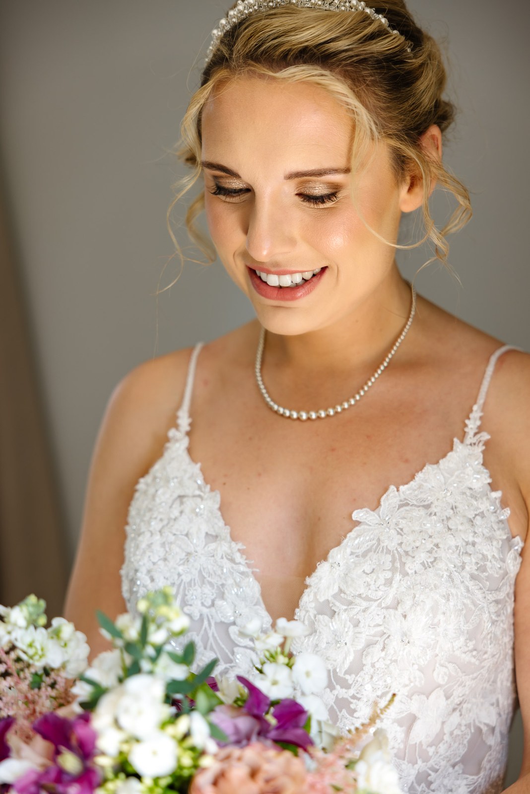 Portrait of the bride in her lace gown holding a colourful bouquet