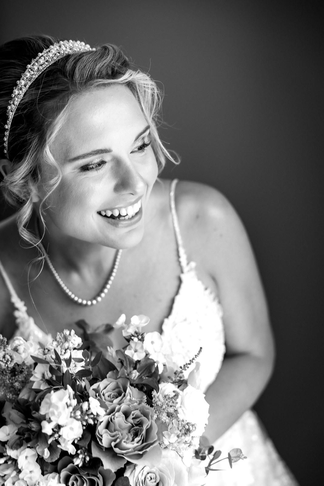 Black-and-white portrait of the bride laughing with her bouquet and tiara