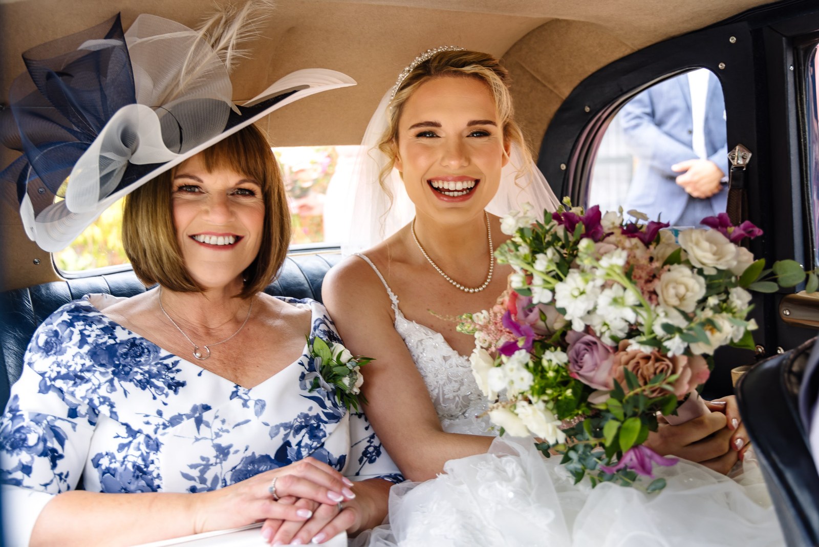 Bride sharing a laugh with her mother in the back of the wedding car