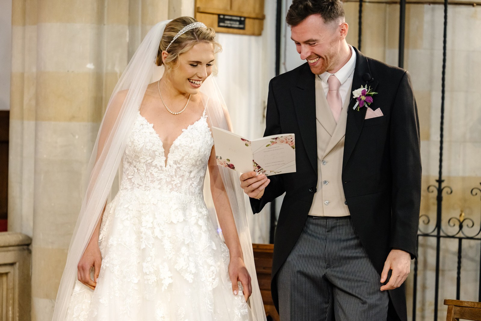 Bride and groom smiling over an order of service during the ceremony