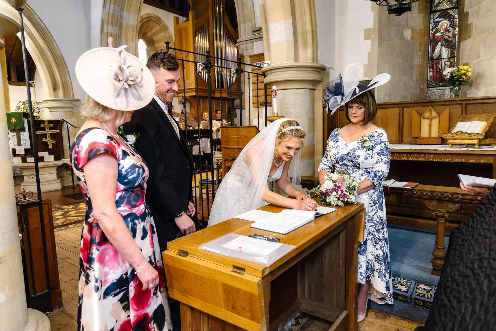 Signing the register at a table with the mothers and groom in the church