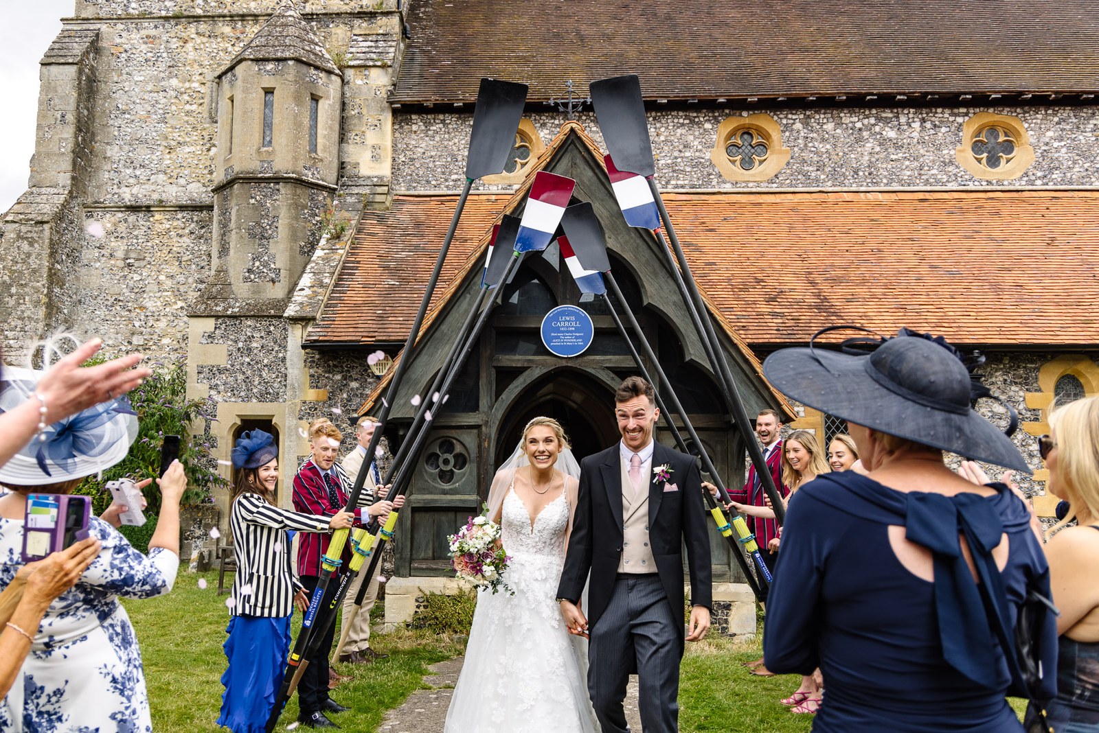 The couple leaving the church beneath an archway of rowing oars