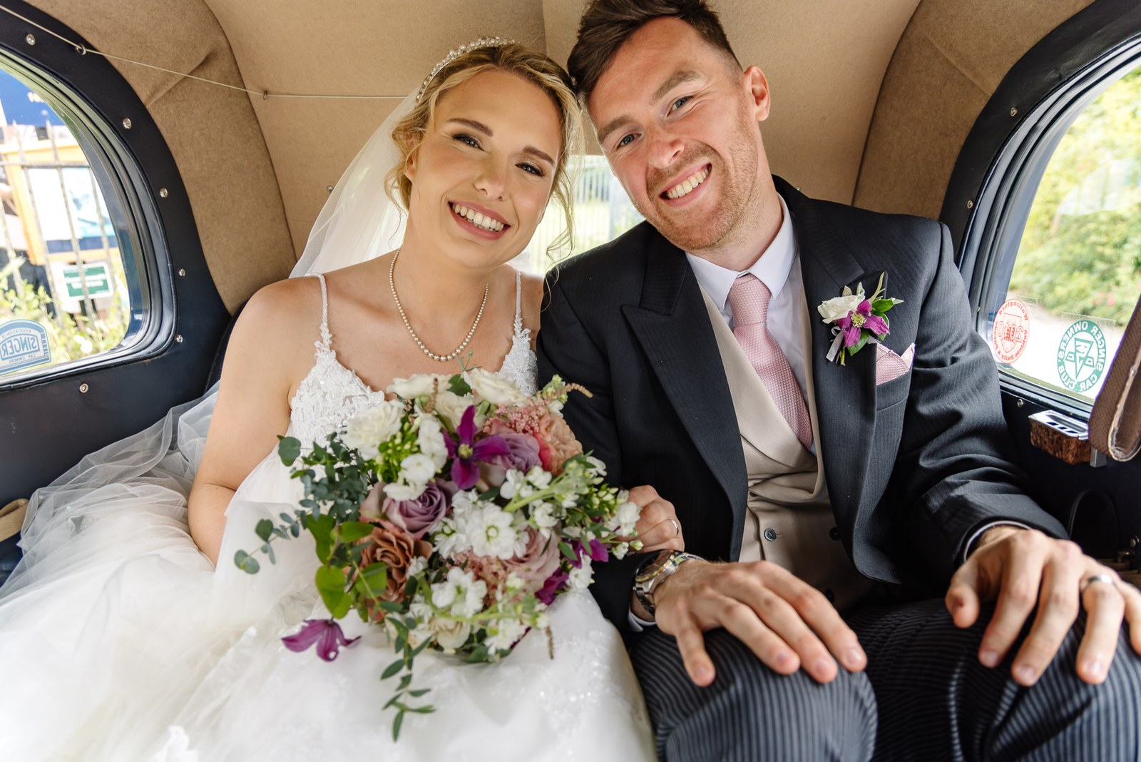 Bride and groom together in the back of the vintage wedding car