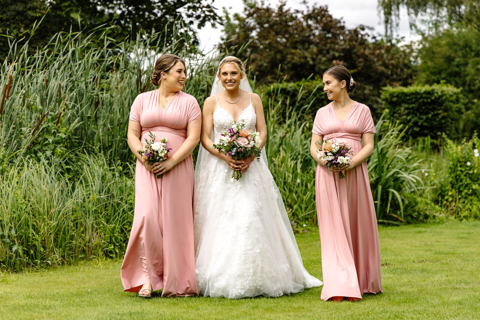 Bride walking across the lawn at The Swan at Streatley with her bridesmaids in pink