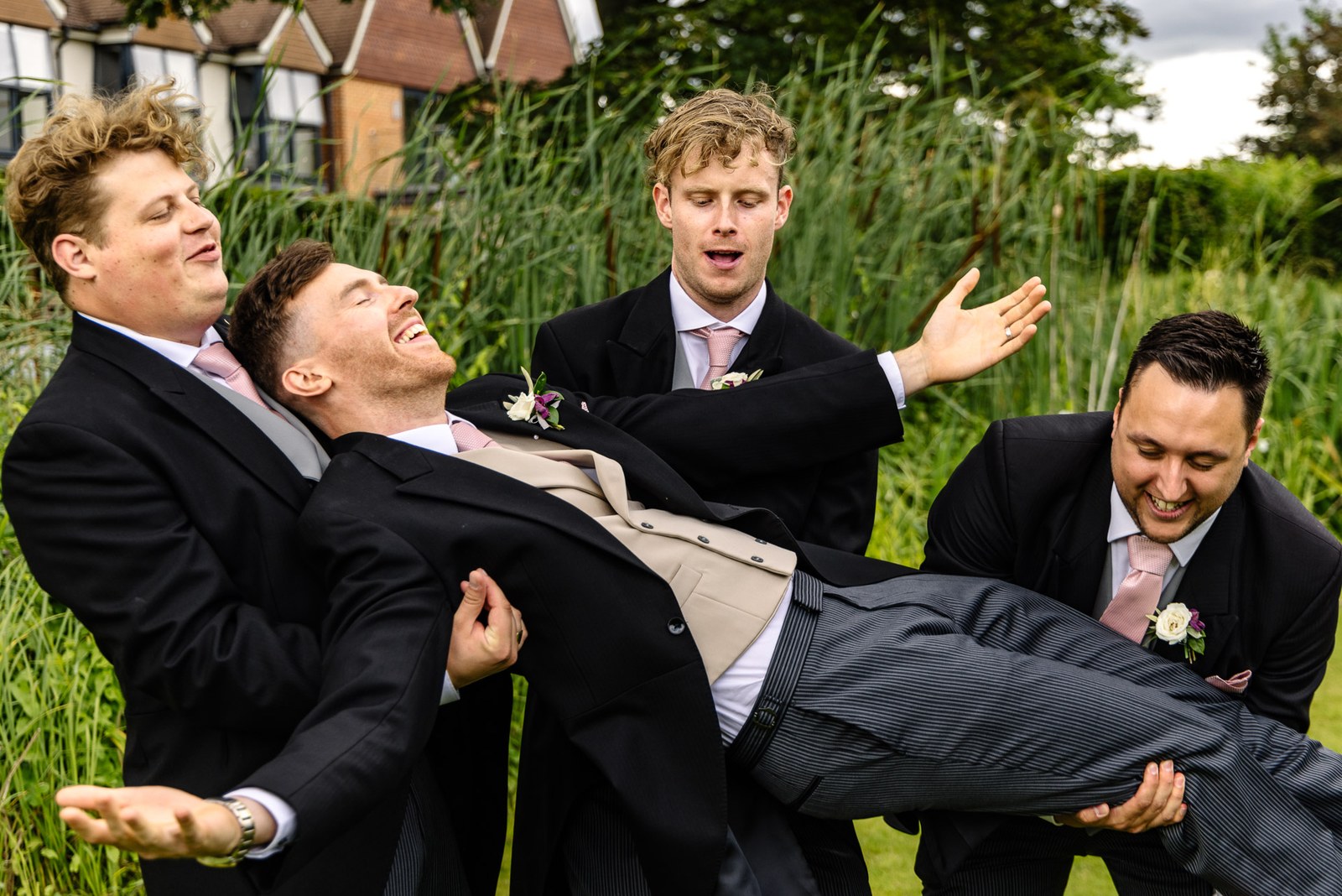 Groomsmen lifting the groom horizontally as they all laugh