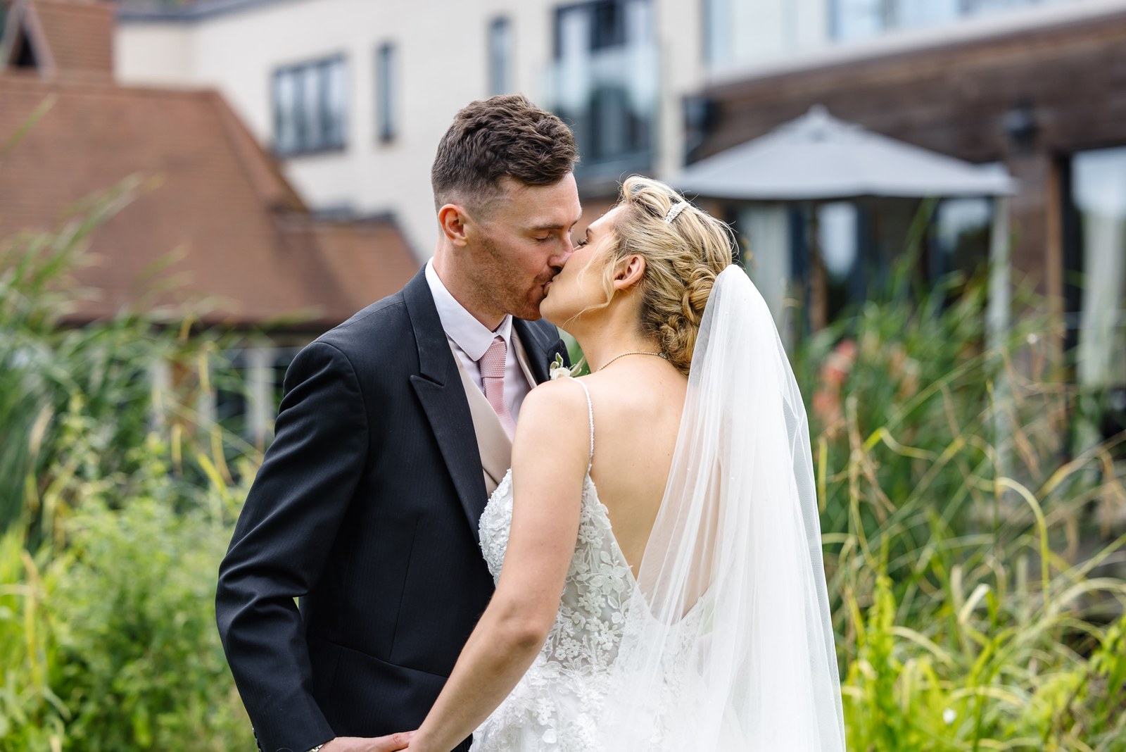 Bride and groom kissing on the riverside lawn at The Swan at Streatley