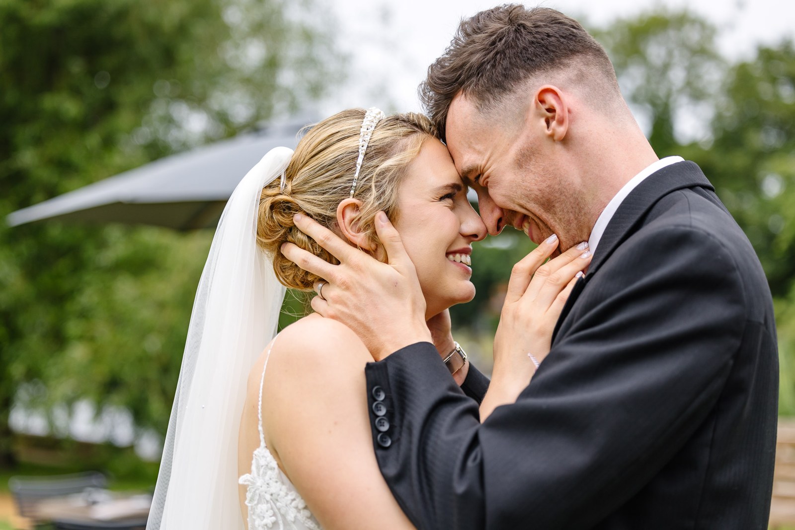 The groom cupping the bride's face as they lean together
