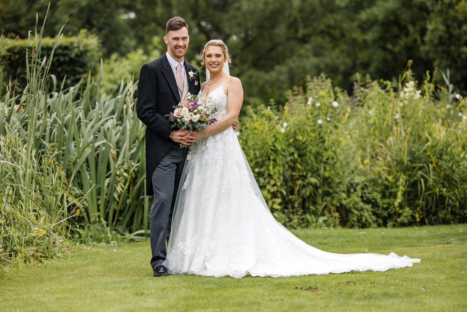 The couple embracing on the riverside lawn at The Swan at Streatley