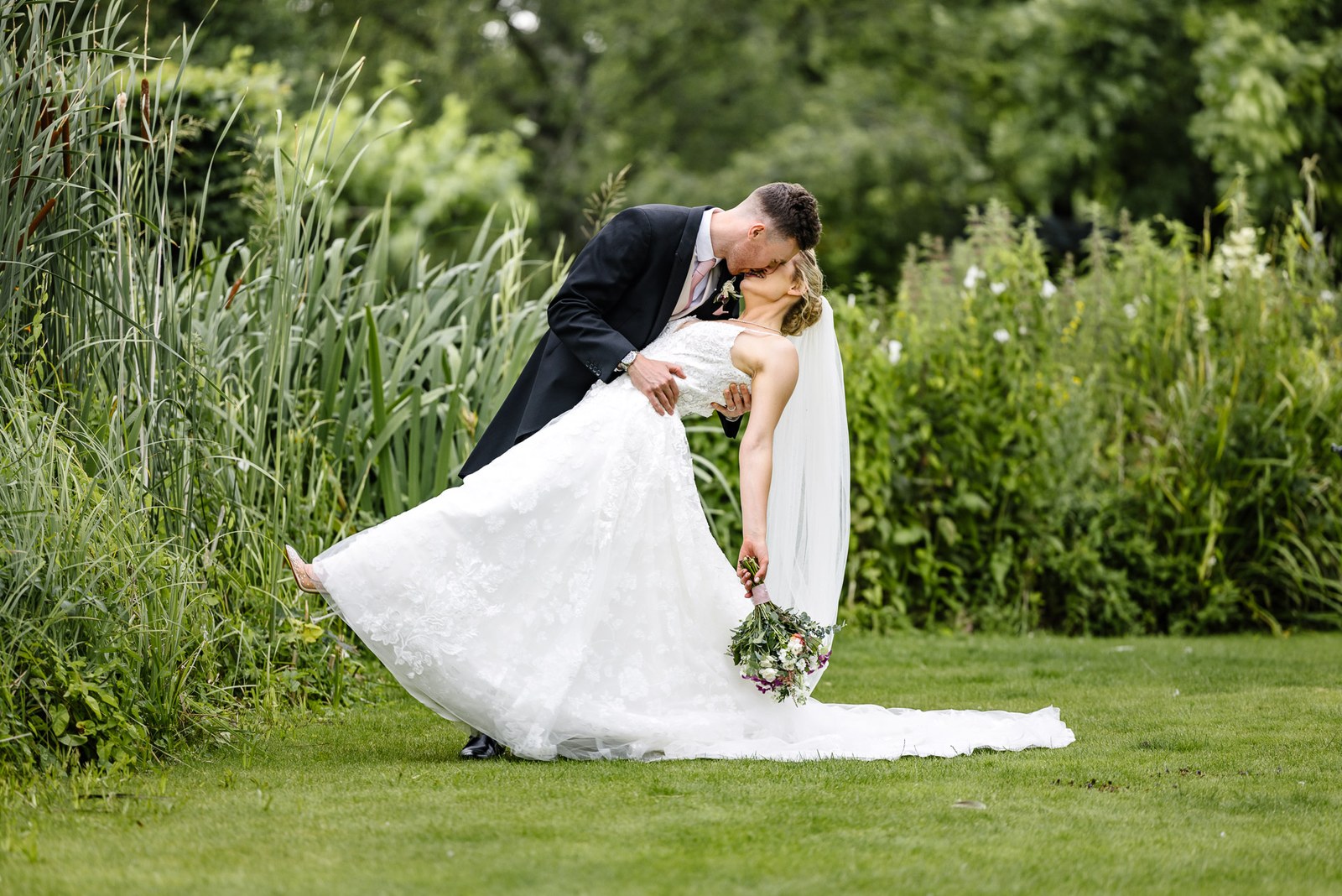 The groom dipping the bride into a kiss on the lawn