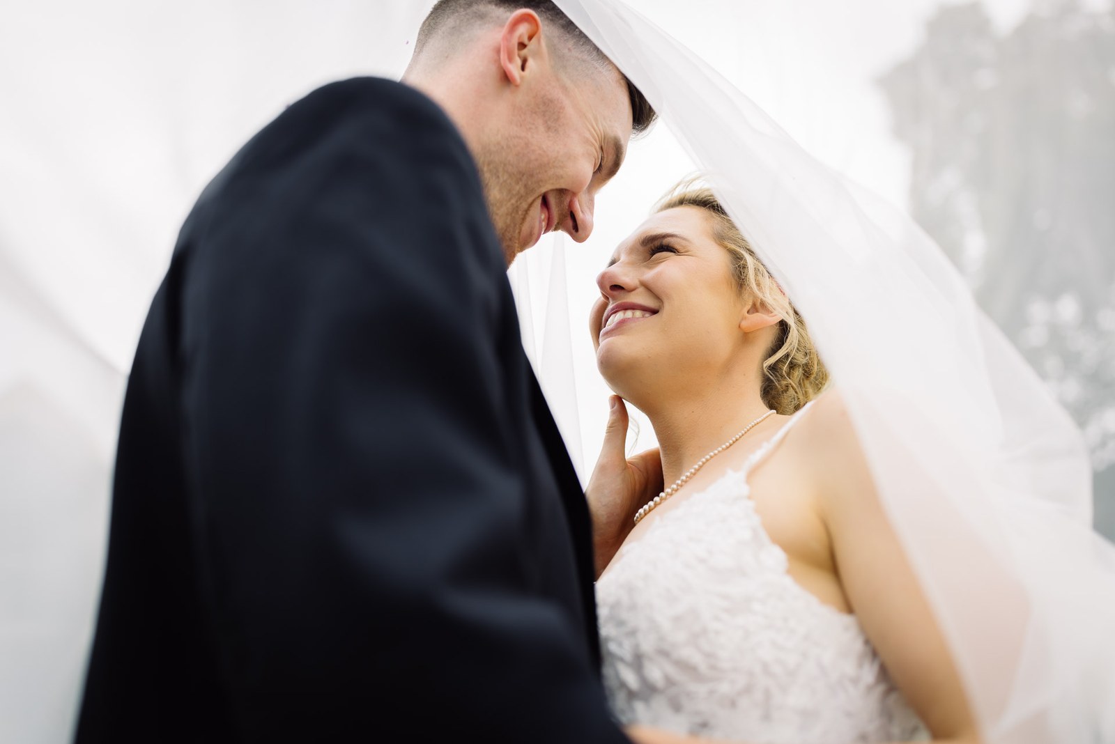 Bride smiling up at the groom from beneath her billowing veil