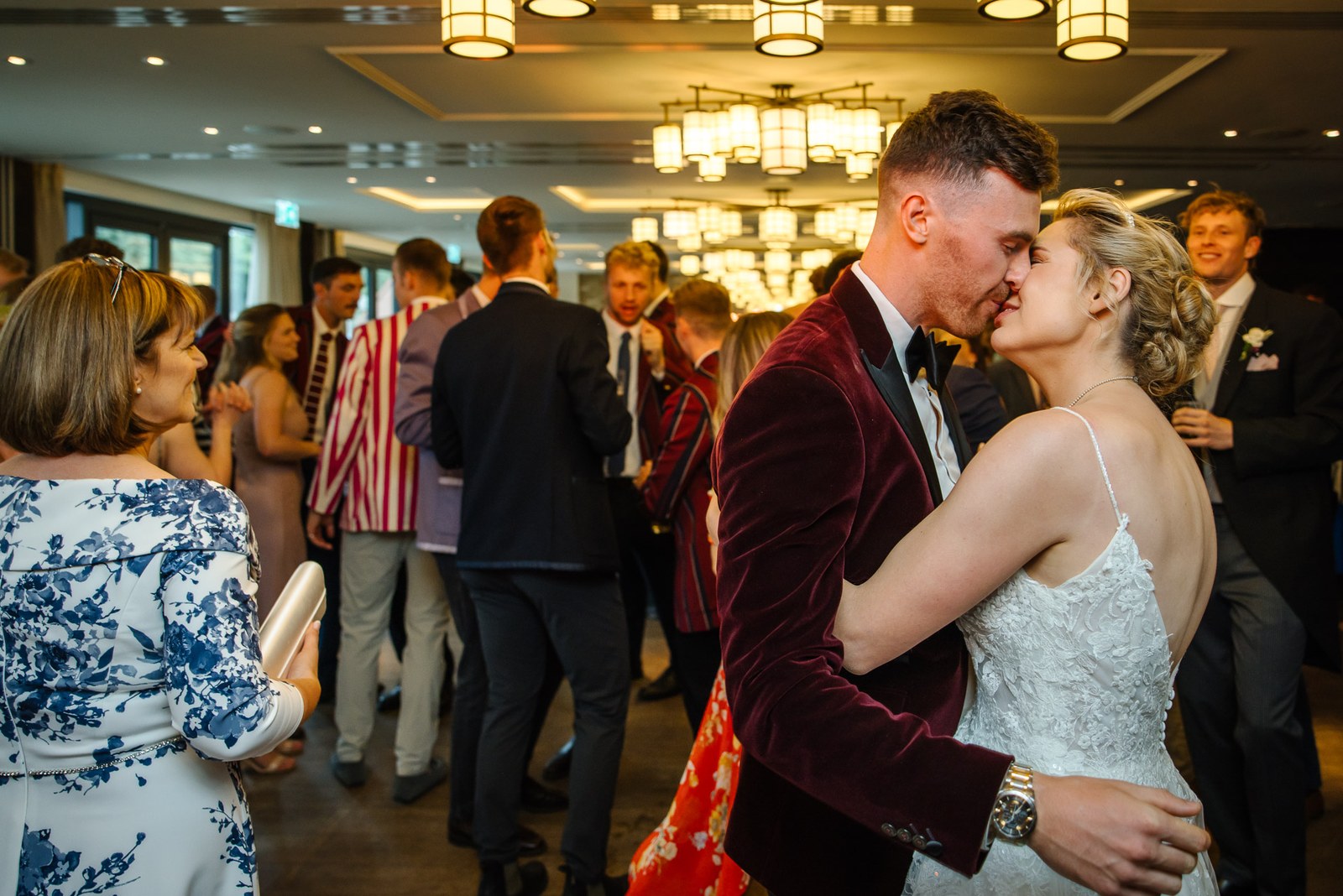 The newlyweds kissing on the dance floor surrounded by guests