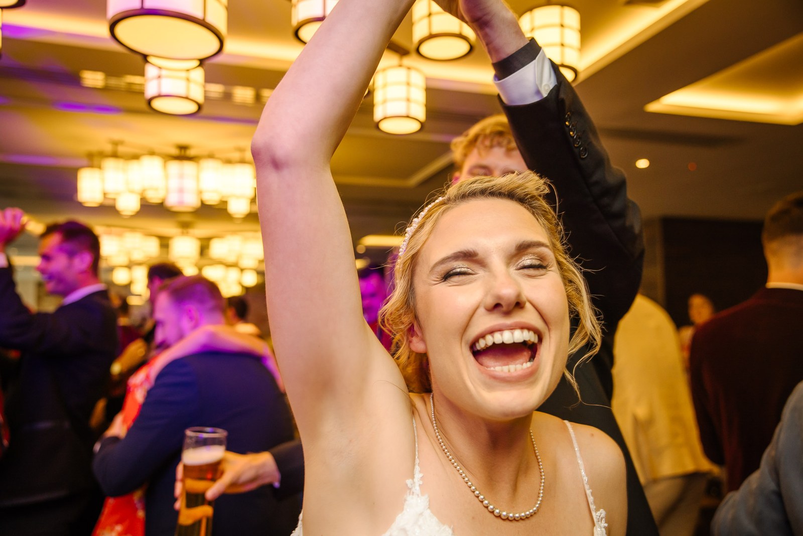 Bride dancing with her arm raised and laughing at the evening reception